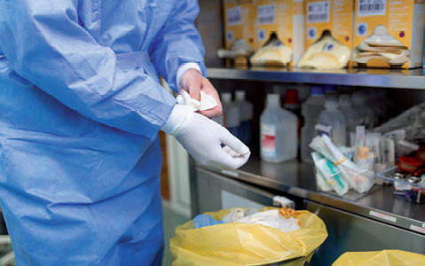 Male surgeon removing surgical gloves in operation theater at hospital